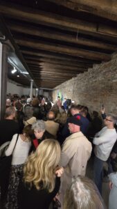 Visitors and invited guests gather inside the Tanzania National Pavilion during the opening reception of the 61st International Art Exhibition – La Biennale di Venezia. The historic exhibition space is filled with attendees listening to the opening remarks.
