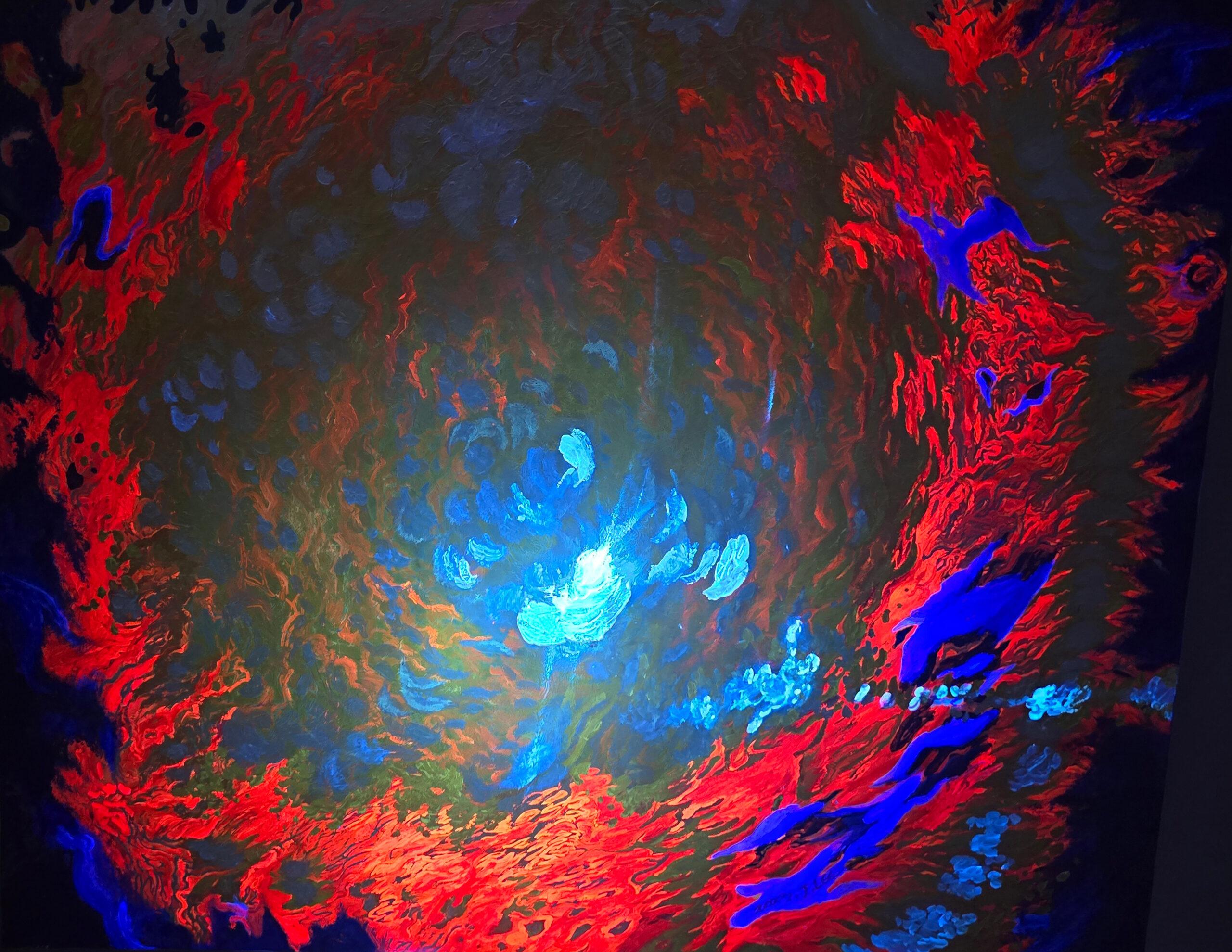 UV view of Eye of the Wise Crow by Jennifer Lee, revealing fluorescent red, blue, and turquoise forms emerging from the darkness under ultraviolet light.
