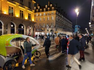 Night view near the Carrousel du Louvre in Paris, France, during Art Shopping Paris 2023. Historic buildings and visitors fill the illuminated streets surrounding the exhibition venue.