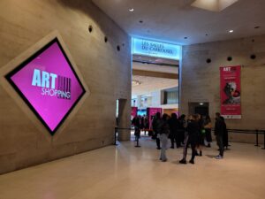 Entrance to Art Shopping Paris 2023 at Les Salles du Carrousel, Carrousel du Louvre, Paris, France. Visitors enter the international contemporary art fair beneath the official event signage.